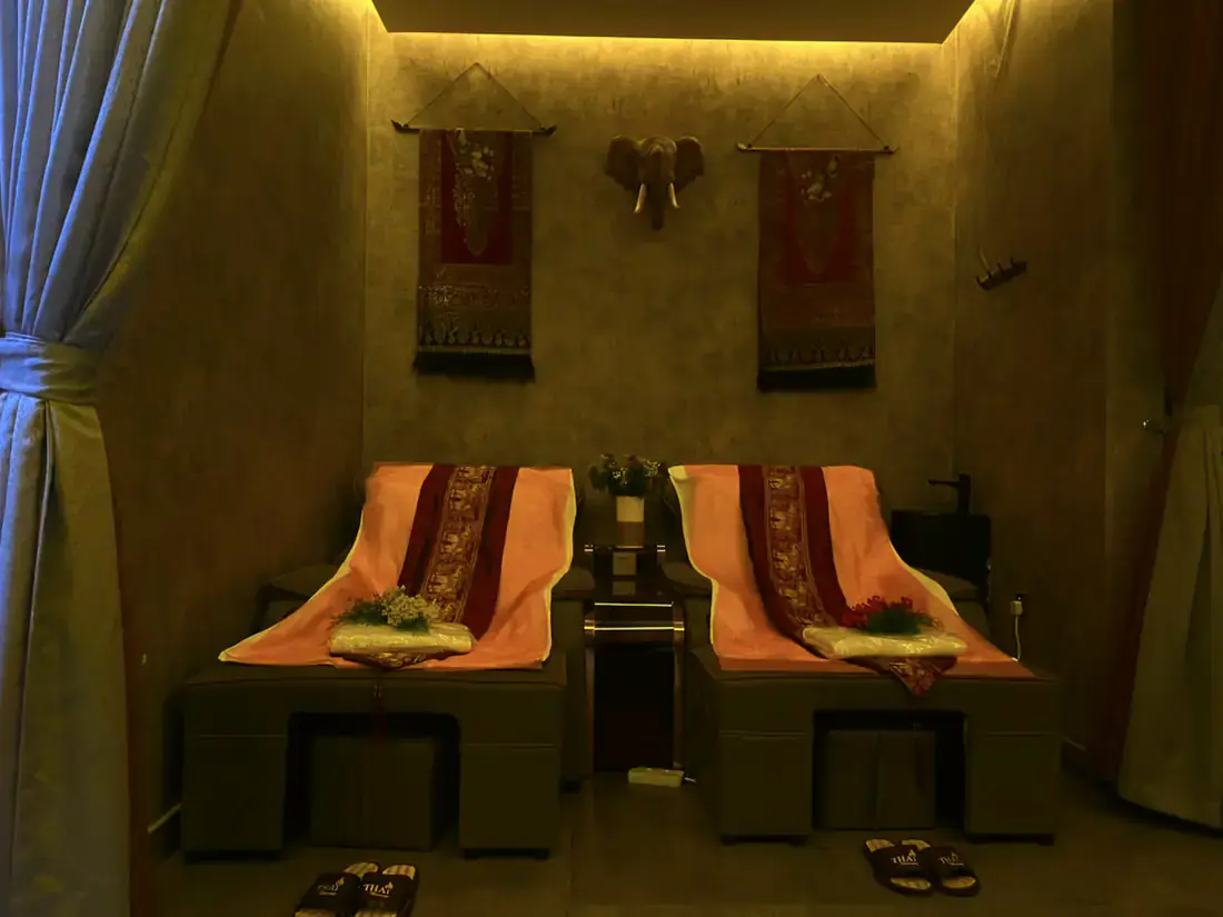 Foot massage room with two reclining chairs dressed in traditional Thai silk runners